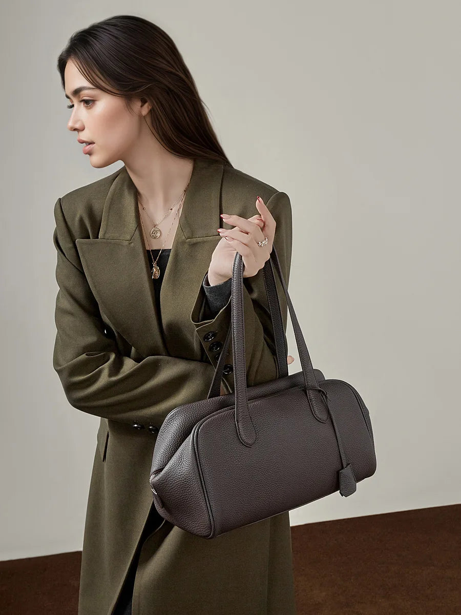 Woman holding a gray handbag against a neutral background, Luxury Genuine Leather Designer Handbags.