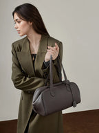 Woman holding a gray handbag against a neutral background, Luxury Genuine Leather Designer Handbags.